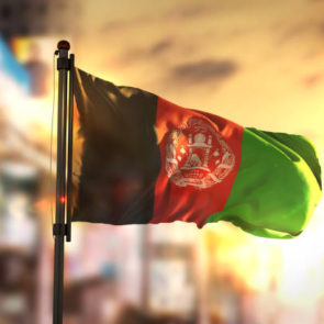 Afghanistan Flag Against City Blurred Background At Sunrise Backlight